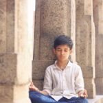 Young visitor sitting peacefully inside an ancient Indian temple, experiencing mindfulness and digital detox through timeless temple wisdom.