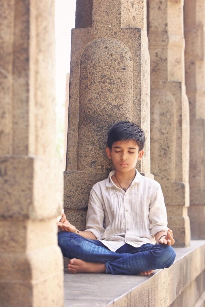 Young visitor sitting peacefully inside an ancient Indian temple, experiencing mindfulness and digital detox through timeless temple wisdom.