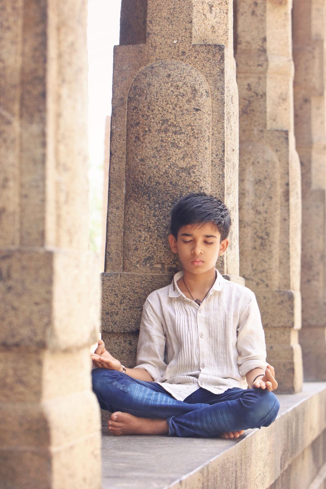 Young visitor sitting peacefully inside an ancient Indian temple, experiencing mindfulness and digital detox through timeless temple wisdom.